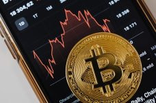 Moneda bitcoin sobre la pantalla de un smartphone.