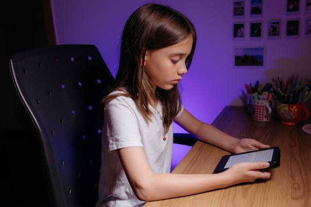 Niña sentada en un escritorio con una tableta.