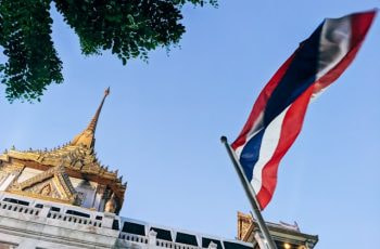 Bandera de Tailandia ondeando frente a un templo.