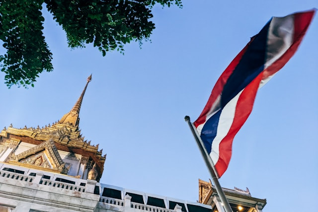 Bandera de Tailandia ondeando frente a un templo.
