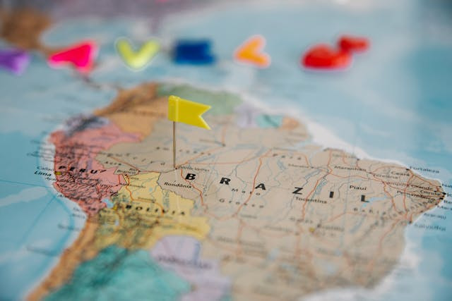Mapa de América Latina con una chincheta con forma de bandera amarilla sobre Brasil.