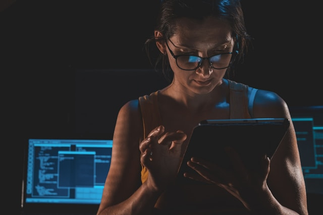 Mujer utilizando una tablet en una habitación con ordenadores.