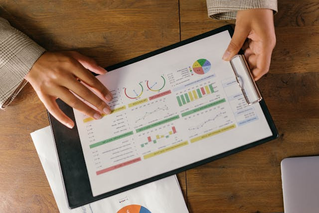 Manos sujetando un dosier con gráficos y diagramas.