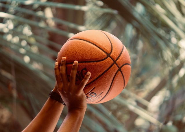 Manos en alto sosteniendo una pelota de baloncesto.