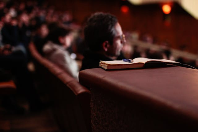 Perfil de un asistente a una ponencia junto a un cuaderno y un bolígrafo.