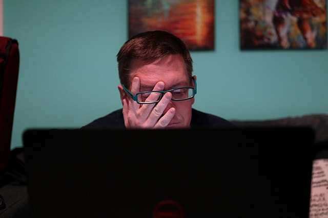 Hombre con gesto de frustración mirando la pantalla de su ordenador portátil.