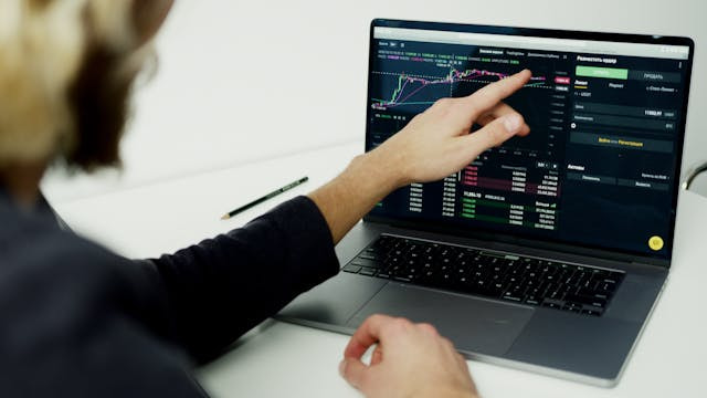 Hombre señalando datos en la pantalla de un portátil.