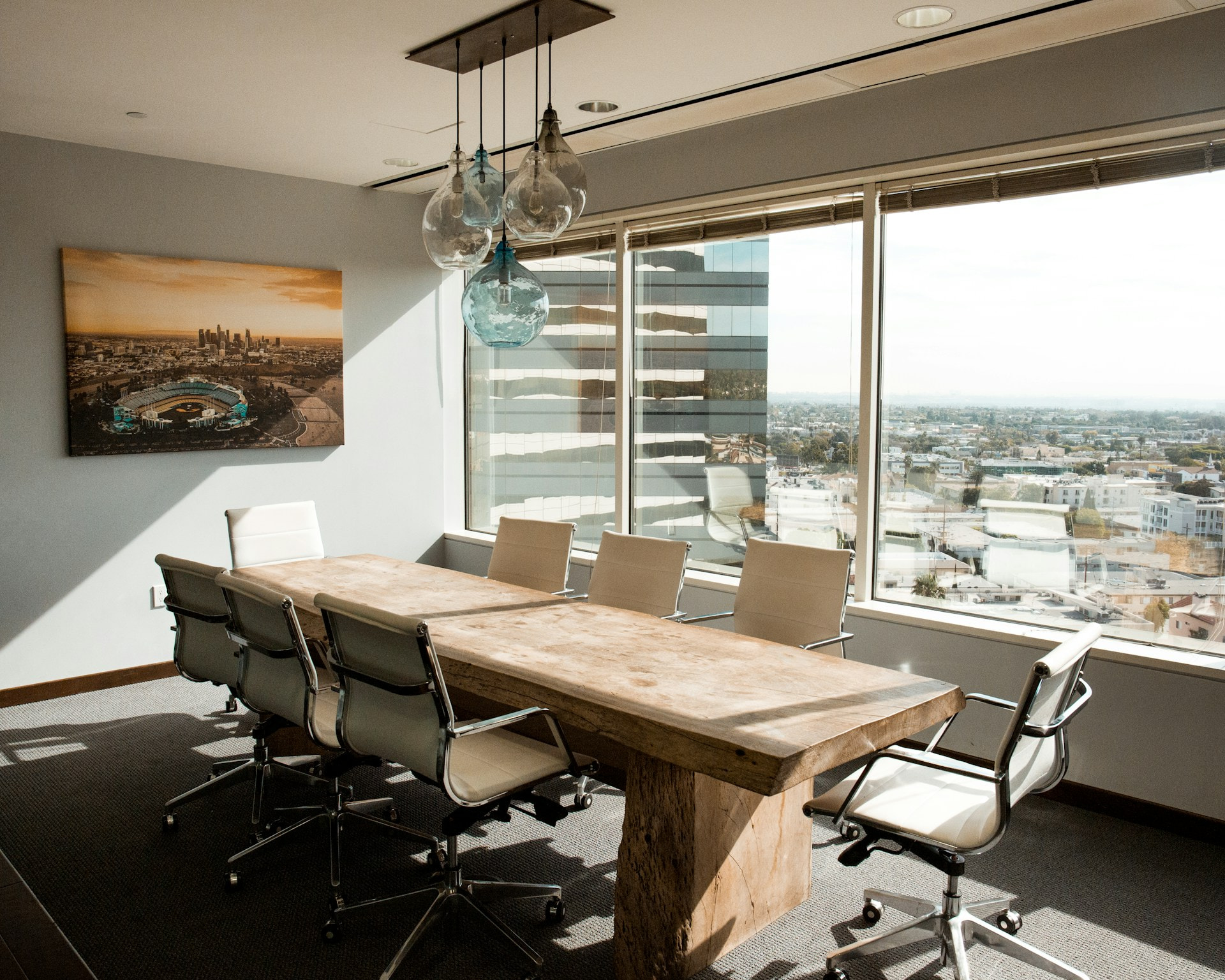 Sala de reuniones con una mesa central y varias sillas junto a una cristalera.