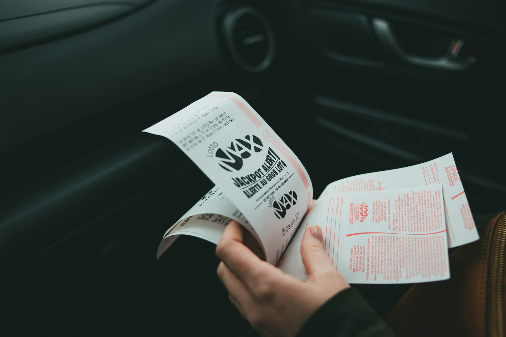 Persona en un coche con varios boletos de apuestas en la mano.