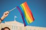Mano alzando una bandera arcoíris o bandera del orgullo LGTB+ creada para luchar por la discriminación laboral LGTB+.
