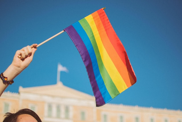Mano alzando una bandera arcoíris o bandera del orgullo LGTB+ creada para luchar por la discriminación laboral LGTB+.