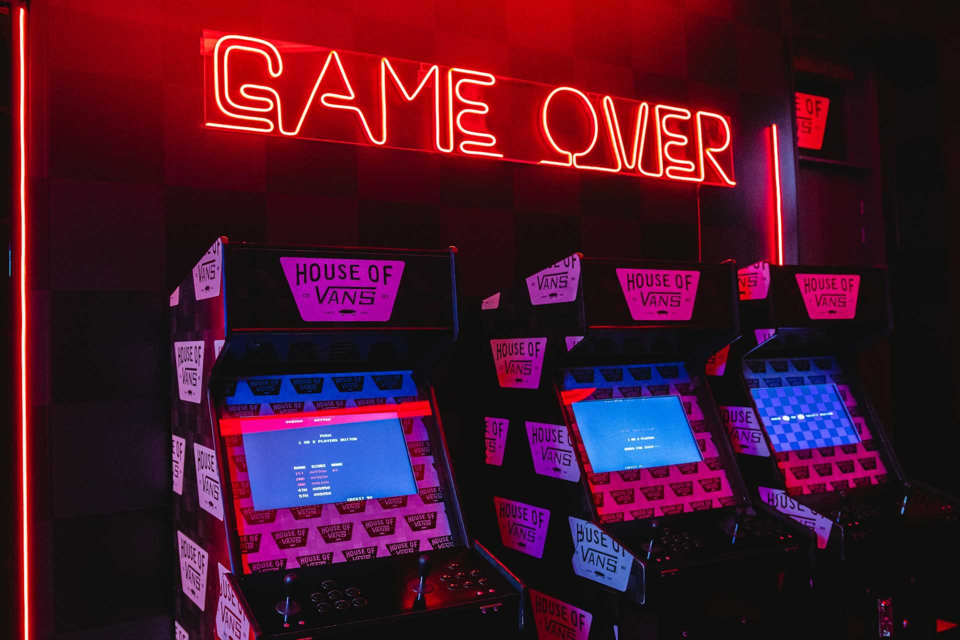 Tres máquinas tragaperras con un letrero de neón encima con la palabra game over.