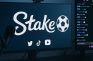 Pantalla con el logo de Stake y redes sociales junto a chat en vivo en Twitch.