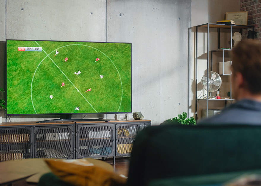 Un hombre viendo un partido de fútbol en una televisión.