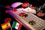 Banderas de España y México junto a un teclado de ordenador y cartas y fichas de póker.
