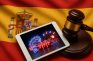 Tablet con símbolos de juego digital sobre bandera de España y mazo judicial.