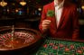Jugador en un casino sosteniendo un trébol de cuatro hojas junto a una ruleta.