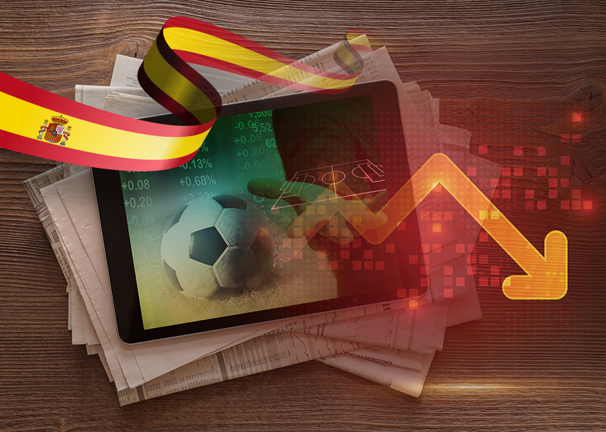 Una tableta mostrando estadísticas de fútbol con una flecha descendente en color rojo y una cinta con la bandera de España.