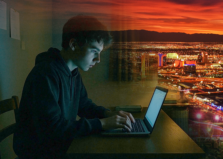 Joven frente a un ordenador con la ciudad de Las Vegas iluminada al fondo.
