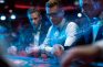 Jugadores concentrados en una mesa de póker con fichas y cartas bajo luces de casino.
