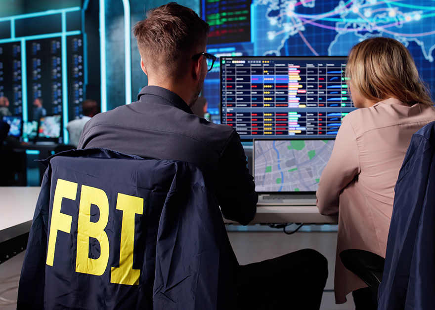 Agentes del FBI observando múltiples pantallas con datos mientras trabajan en un centro de control.