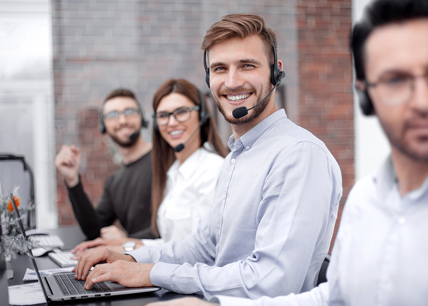 Personas con auriculares trabajando con portátiles en una mesa.