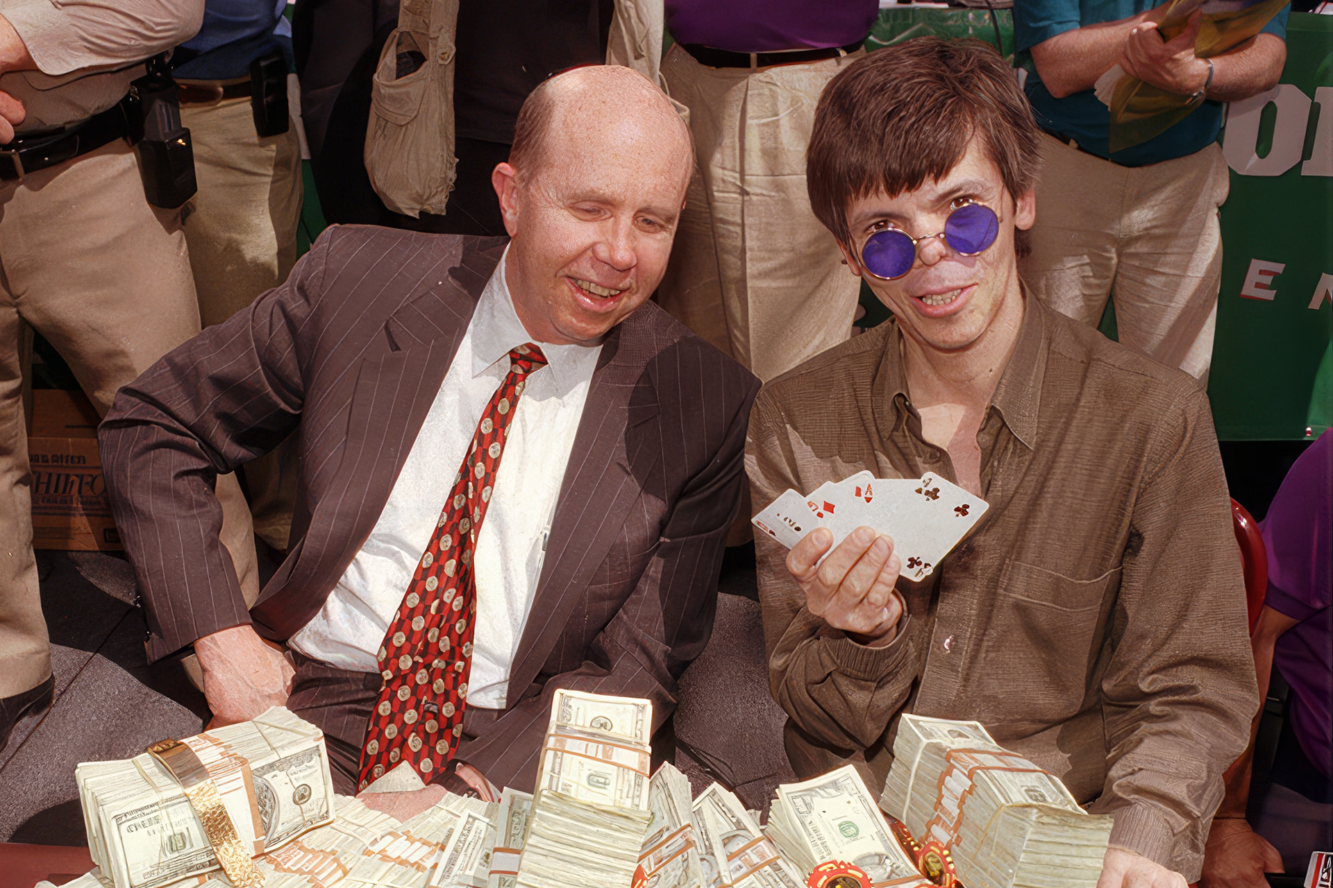 Stu Ungar sentado ante una mesa llena de fajos de billetes y cartas de póker.