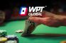 Mano levantando cartas sobre mesa de póker con logo “WPT Global”.