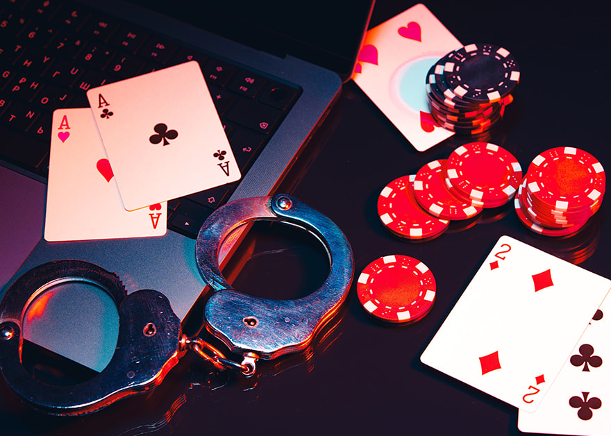 Esposas, fichas de póker y cartas sobre un portátil.