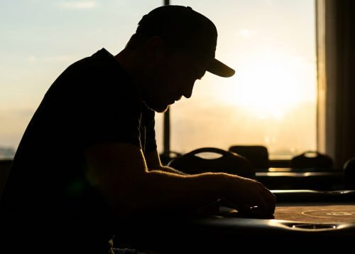 Silueta de un hombre con gorra sentado en una mesa de póker.