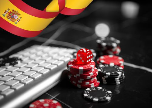 Fichas y dados rojos junto a teclado, con bandera de España.