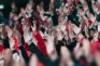 Aficionados de fútbol levantan las manos y aplauden en las gradas durante un partido Copa Mundial de la FIFA.