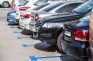 Fila de coches aparcados en plazas de zona azul al aire libre durante un día soleado en España.