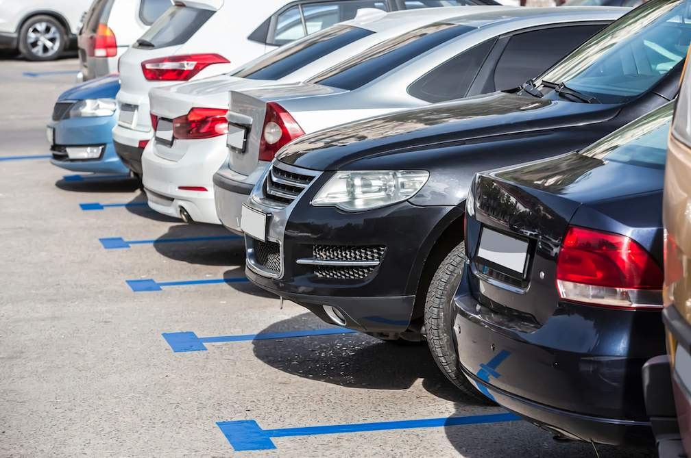 Fila de coches aparcados en plazas de zona azul al aire libre durante un día soleado en España.