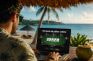 Jugador de póker online con portátil en terraza tropical frente al mar en verano