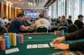 Jugadores en las mesas de una sala de torneo de póker con fichas y cartas sobre el tapete