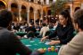 Crupier reparte cartas en una mesa de póker durante un torneo en vivo con jugadores y fichas