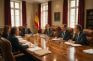 Reunión institucional en torno a una mesa con documentos y la bandera de España al fondo