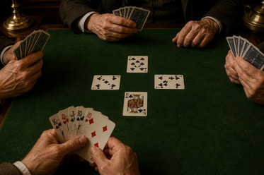 Cuatro jugadores disputando una baza de whist sobre el tapete.