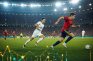 Futbolista con camiseta roja conduce el balón en un estadio lleno durante un partido europeo