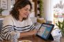 Mujer de mediana edad jugando al bingo online en una tableta en el salón de su casa