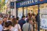 Cola de compradores ante una administración de Lotería con décimos de Navidad en el escaparate