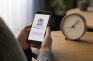 Persona con una app bancaria en el móvil junto a un reloj mientras espera una retirada