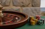 Ruleta de casino con fichas apiladas sobre una mesa verde
