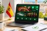 Portátil con juegos de casino online junto a una bandera de España